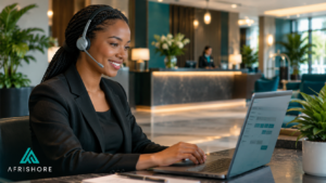 Hotel reservations agent wearing a headset taking a guest booking call, with a calm hotel lobby visible through a glass wall behind